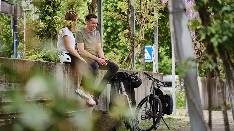 Zwei Radlerinnen sitzen auf der Mauer grüne Stadt Zwei Radlerinnen sitzen auf der Mauer grüne Stadt