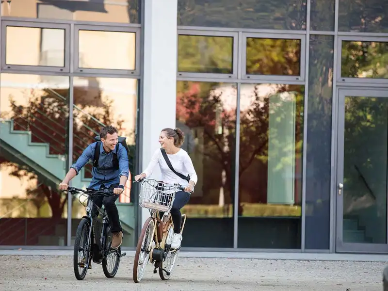 Zwei Radfahrer:innen fahren zufrieden in den Feierabend Zwei Radfahrer:innen fahren zufrieden in den Feierabend