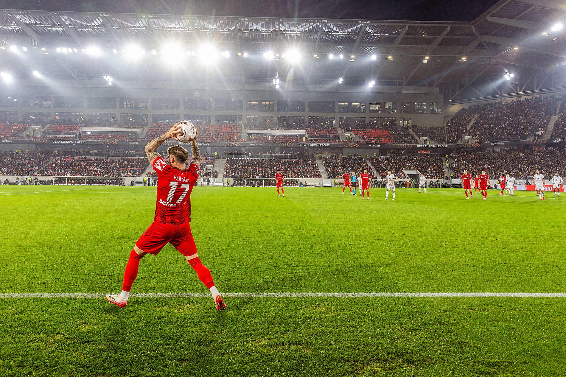 Der SC-Freiburg Spieler Kübler im roten Trikot macht einen Einwurf von der Seitenlinie.